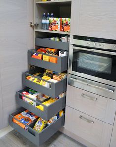 a kitchen with an oven, microwave and food storage drawers on the floor in front of it