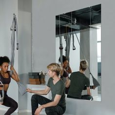 a group of people doing exercises in front of a mirror with mirrors hanging from the ceiling