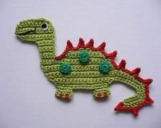 a crocheted green and red dinosaur brooch