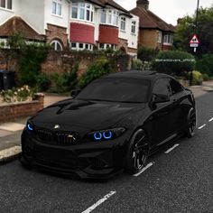 a black car is parked on the side of the road in front of some houses