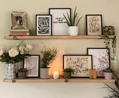 two shelves with pictures, flowers and candles on them in front of a white wall