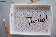 a tray with the word fa - da written in black ink on it next to some paintbrushes