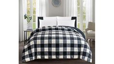 a black and white plaid comforter set on a bed in a room with windows