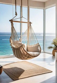 a hammock hanging from the ceiling in front of a window overlooking the ocean