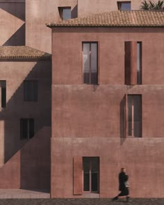 a person walking past a tall pink building