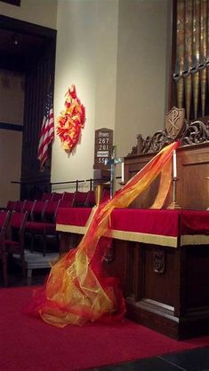 an organ in the middle of a church with red and yellow cloth draped over it