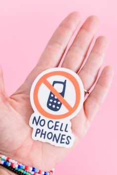 a hand holding a no cell phones sticker