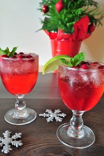 three glasses filled with red liquid and garnished with green leaves, snowflakes and candy canes