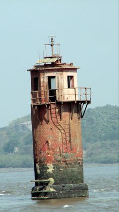 an old rusted tower sitting in the middle of water