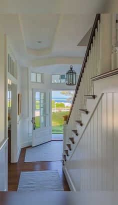 an entry way leading to a house with white walls and wood floors, along with a blue rug on the floor