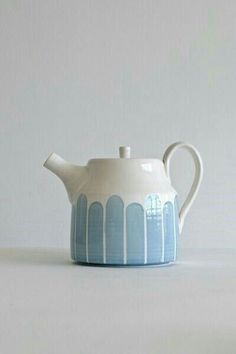 a white and blue tea pot with lines painted on it