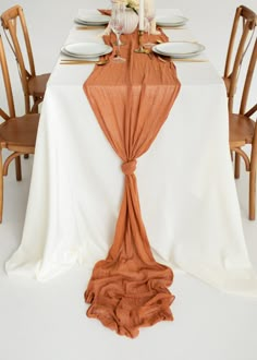 the table is set with white plates and orange napkins