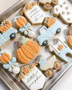 decorated cookies in the shape of cars and pumpkins are on a tray with writing