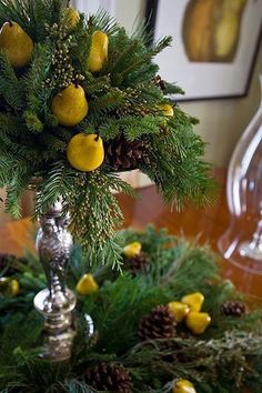 a christmas tree with pine cones and lemons on it's branches in a silver vase