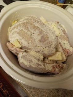 a white bowl filled with chicken and potatoes on top of a counter next to an oven