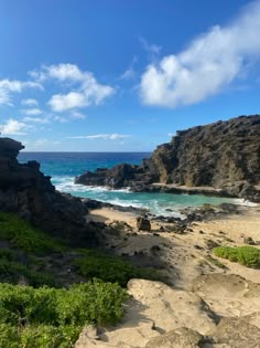 a rocky beach next to the ocean under a blue sky