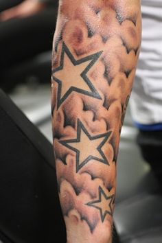 a man's arm with clouds and stars on it