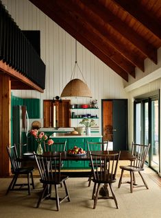 a dining room table and chairs with green cabinets in the back ground, along with open doors leading to an outdoor deck