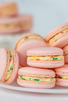 pink macaroons with yellow and green sprinkles are on a plate