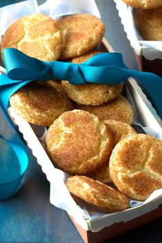 two boxes filled with cookies sitting on top of a wooden table next to blue ribbon