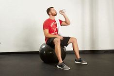 a man sitting on an exercise ball drinking water