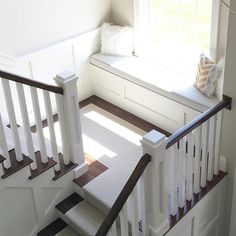 the stairs lead up to a window seat with pillows on it's back end