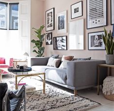 a living room with pink walls and pictures on the wall above it's couch