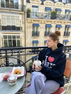 a woman sitting on top of a balcony next to a table with donuts and coffee