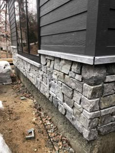 the side of a house that is being built with some rocks on top of it