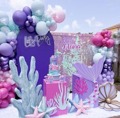 there are many balloons and decorations on the table for a mermaid themed birthday party or baby shower