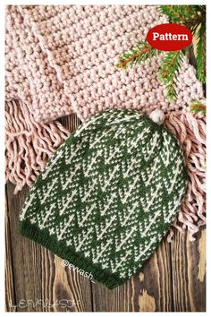 a green and white knitted hat sitting on top of a wooden floor next to a pine tree