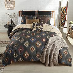 a bed covered in a black and brown comforter next to a white brick wall