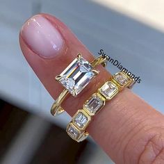 a woman's hand holding two rings with different stones on the middle and sides