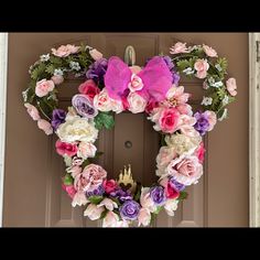 a wreath made out of flowers is hanging on the front door with a purple bow