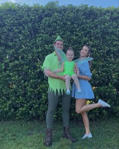 a man and woman dressed up as tinkerbells pose for a photo in front of a hedge