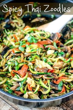 a pan filled with noodles and vegetables on top of a wooden table