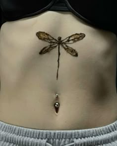 the back of a woman's stomach with a dragonfly tattoo on her side