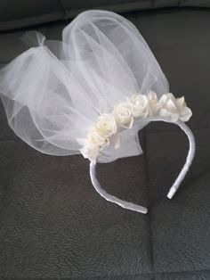 a bridal headband with flowers and tulle on the back of a couch