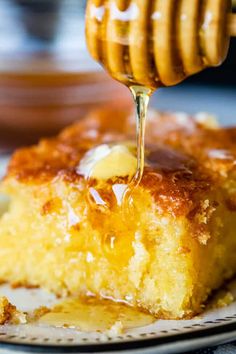 a piece of cake on a plate with honey being drizzled over it