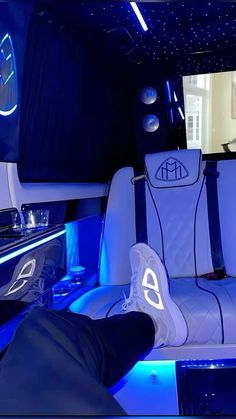 the interior of a car with blue lights and white seats, including one person's feet up