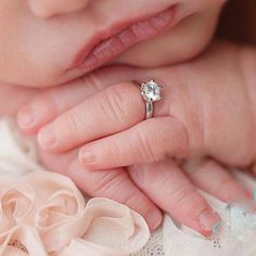 a close up of a person holding a baby's hand with a ring on it