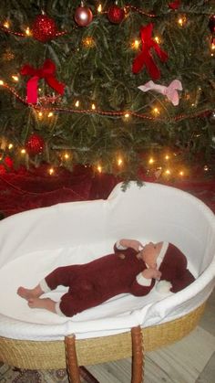 a baby laying in a bassinet next to a christmas tree