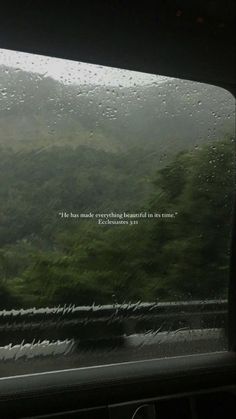 rain drops on the windshield of a car as it drives down a mountain road in the rain