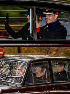 the queen and prince are riding in an old car with their hats on, waving