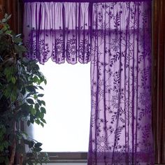 a purple curtain hanging in front of a window next to a potted plant