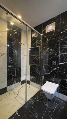 a bathroom with black marble walls and flooring, along with a walk in shower