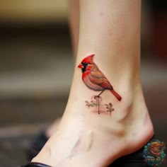 a small red bird on the ankle tattoo is shown in front of a woman's foot