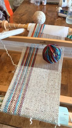 a ball of yarn sitting on top of a table next to a weaving loom