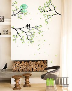 two birds sitting on a tree branch in front of a white wall with black and gold accents