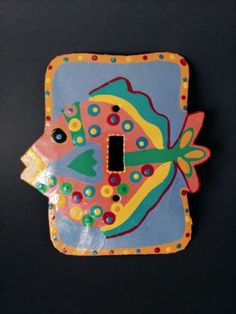 a decorative light switch cover with a colorful fish on it's front and side